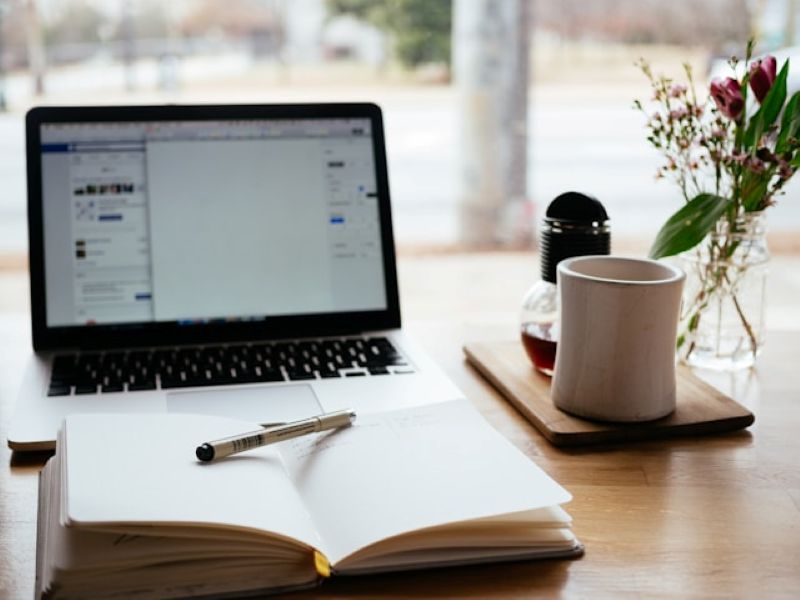Protecția muncii în telemuncă – reguli esențiale pentru un mediu de lucru sigur Spațiu de lucru modern, organizat pentru telemuncă, cu laptop, agendă și cafea.